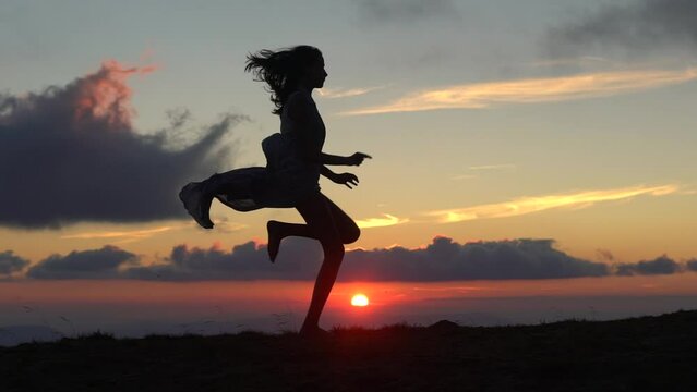 Jumping woman and sunset silhouette. Girl movement over sunset light. Free young woman at golden sunset. Freedom and success concept, enjoying nature.