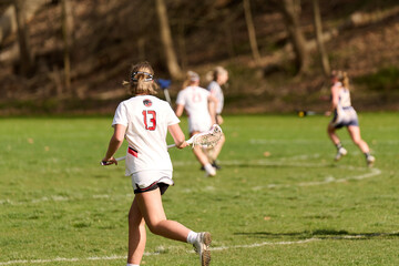 Obraz na płótnie Canvas SEWICKLEY, PA, USA - APRIL13th 2022: Teenage girls from Sewickley Academy play senior school varsity lacrosse game against Freeport High School. There were lots of goals and action on this sunny day.