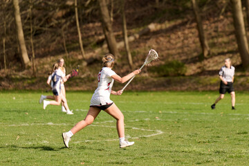 Obraz na płótnie Canvas SEWICKLEY, PA, USA - APRIL13th 2022: Teenage girls from Sewickley Academy play senior school varsity lacrosse game against Freeport High School. There were lots of goals and action on this sunny day.