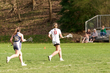 SEWICKLEY, PA, USA - APRIL13th 2022: Teenage girls from Sewickley Academy play senior school varsity lacrosse game against Freeport High School. There were lots of goals and action on this sunny day.