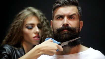 Female barber. Woman hairdresser cuts beard handsome man at barbershop. Beard care.