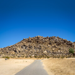 Asphalt walking path to a rock formation hill in the Mojave Desert