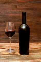 Red wine in glass, black bottle on wooden rustic table, alcohol drink, cocktail, still life copy space, dark photo, mock up template