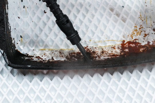 A Man Cleans A Dirty Baking Dish With A Thick Layer Of Carbon With A Special Steam Cleaner Nozzle. Glass Dishes For Baking With Soot, Carbon Deposits, Old Dried Fat Are Cleaned With A Steam Generator.