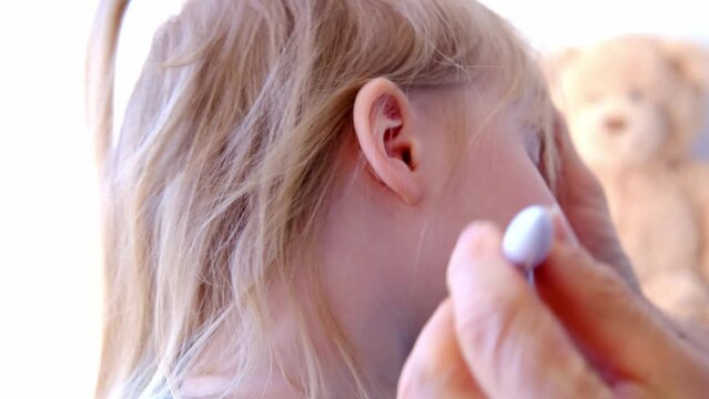 close-up ear of small child, doctor cleans baby's ear with spiral silicone instrument, concept of hearing organs health, happy childhood, prevention of otitis media, hearing loss, World Hearing Day