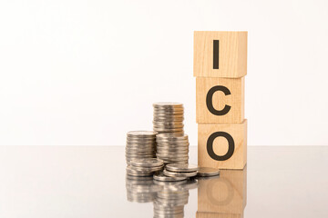 ICO - text on wooden cubes on white background with coins