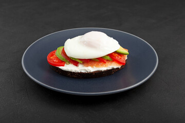 Sandwich or toast with salmon, avocado, tomatoes and cream cheese on plate, close-up