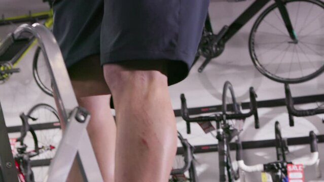 Bike shop employee uses step stool to retrieve a bike