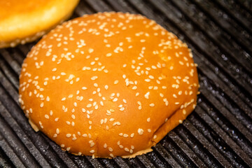 Making and grilling hamburger buns with sesame on coal grill. Preparing roasted food on barbecue...