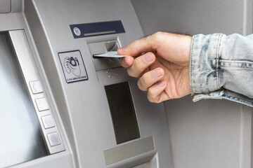 Male hand inserting ATM card into ATM bank machine