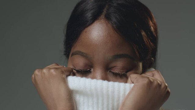 Shy young pretty african american girl hiding face behind wool knitted sweater collar. Laundry advertising. ProRes codec