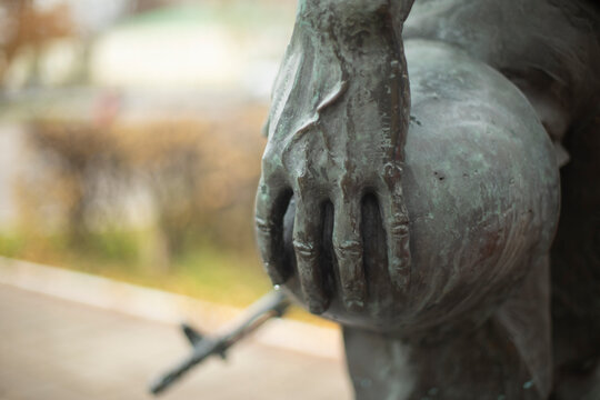 Military helmet in hand. Monument to soldier is in detail.