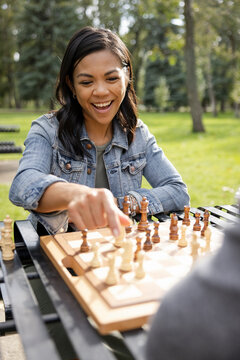 Happy woman playing chess in park