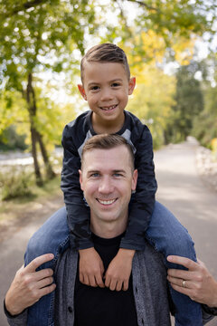 Portrait happy father carrying son on shoulders in park