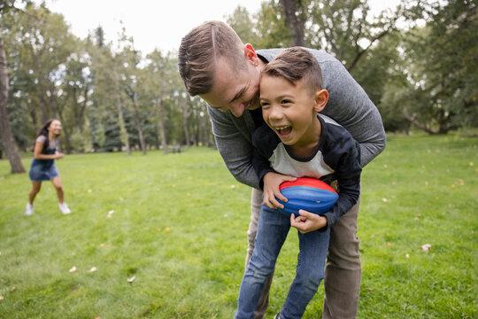 Happy Father And Son With Football In Grassy Park