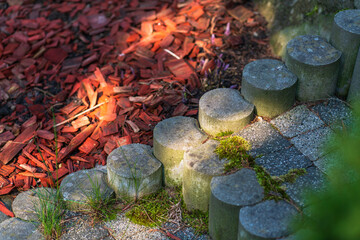 Close-up of an old garden path made of moss-covered stones with a sunbeam, the ground is covered...
