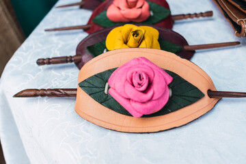 colored hair clips embroidered and woven on alpaca fiber looms and with leather with ancestral designs and geometric figures in bright colors arranged on a table with a white tablecloth