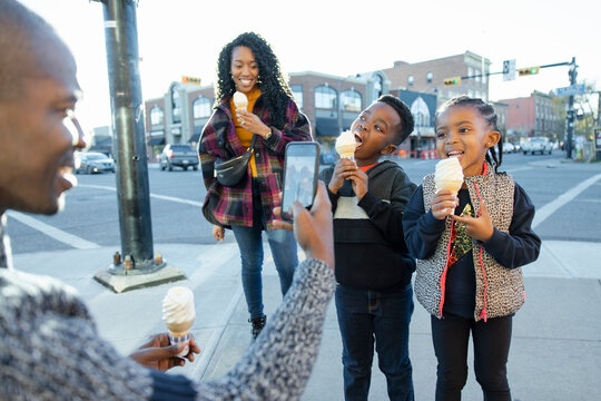 Father Photographing Kids Eating Ice Cream Cones On City Sidewalk