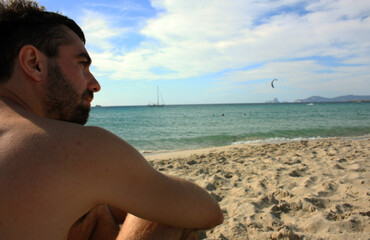 young caucasian man in costume enjoy the spectacle of his beach holidays in formentera in front of the blue sea