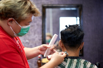 Barber shaving the nape of a client using a clipper and comb