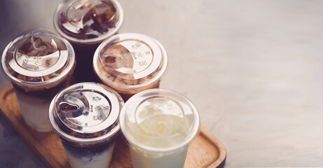 Cold brewed iced latte coffee, Ice coffee latte cup in a plastic glass on. barista hand in coffee cafe.banner background.Cold brew coffee ads.Latte with milk caffeine.plastic ice cup.Arabica roasted.