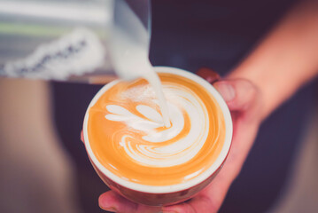 Cappuccino or latte with frothy foam, blue coffee cup top view closeup on barista hand background.Cafe and bar, barista making latte art.fresh cappuccino coffee mug in cafe.caffeine roasted arabica.