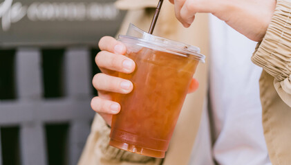 Cold brew iced americano coffee in A bio cup on man hand drinking.herbal ice tea drink.Ice aroma black coffee, espresso, americano with medium roasted coffee beans.hipster teen in cafe with cold brew.