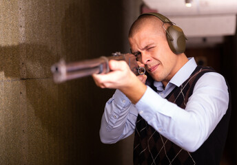 Man shoots a double-barreled gun at a shooting range
