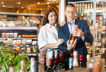 Married couple choosing wine at grocery supermarket