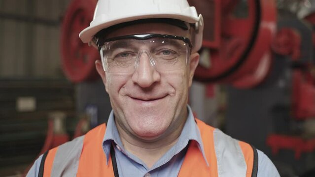 Portrait of happy professional heavy industry male engineer confident wearing safety goggles and hard hat with smiling in factory. Closeup of senior man worker standing looking at camera in workplace.