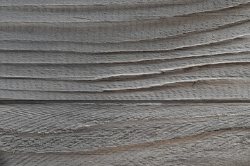 The texture of a relief gray wooden surface covered with cracks under the influence of time.