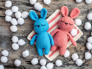 Handmade toys, amigurumi bunnies blue and pink on a gray background