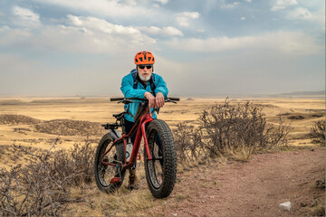 Fototapeta na wymiar senior male cyclist with a fat mountain bike on a single track trail in northern Colorado grassland, early spring scenery in Soapstone Prairie Natural Area near Fort Collins