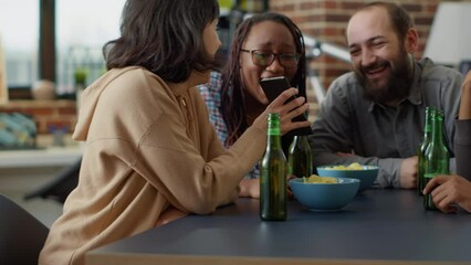 Millennial people sharing social media memes on mobile phone, having fun with online internet and modern technlogy. Group of friends laughing together with smartphone network app.