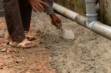 Indian labour plastering floor using trowel and cement manually, Stock image.