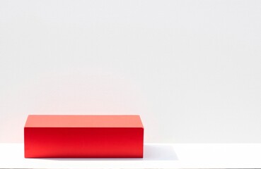 The red boxes on the podium stage are shaded by sunlight on a white backdrop for a product display stand.