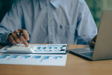 Close-up of a financial businessman hand pressing a white calculator to calculate numbers from...