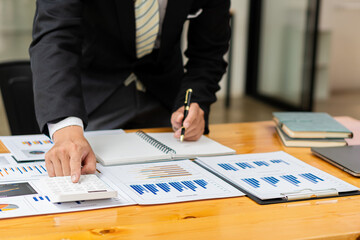 Close-up of a financial businessman hand pressing a white calculator to calculate numbers from company accounts to prepare annual financial reports. Concept of validation of financial numbers