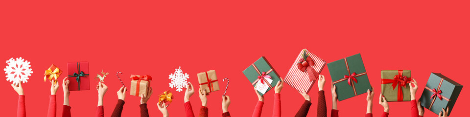 Many hands with Christmas gifts and decorations on red background - Powered by Adobe