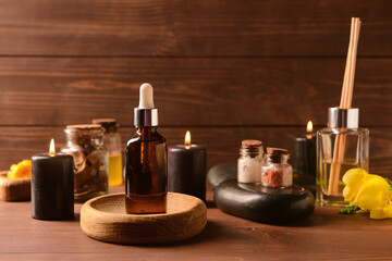 Bottle of essential oil and spa accessories on wooden table