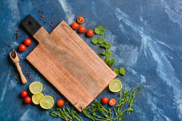 New cutting board with tomatoes and lime on blue background