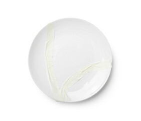 Broken ceramic plate with adhesive tape on white background