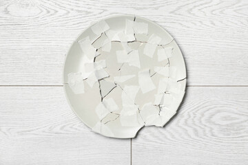 Broken ceramic plate with adhesive tape on light wooden background