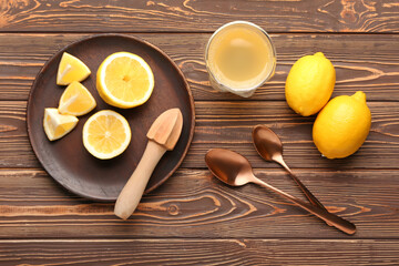 Composition with ripe lemons, juicer and glass of juice on wooden background