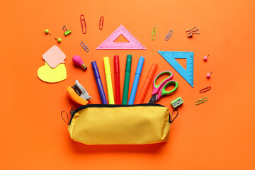 Pencil case with school stationery on orange background, flat lay