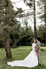 Beautiful wedding couple of newlyweds hugging on the background of the forest