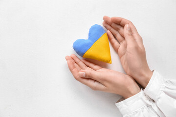Hands with heart in colors of Ukrainian flag on light background