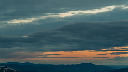 Obraz premium Gentle hills in gray haze on horizon. Rock ridge under sunset sky. Clouds gathered on mountain valley. Mystery of Future Weather Uncertainty