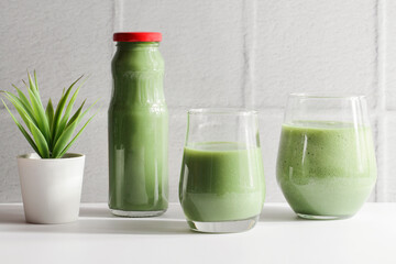 Obraz na płótnie Canvas green smoothie in glasses on white ceramic tile background, copy space. vegan food concept. Healthy, diet, detox food.Healthy breakfast. 