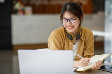 Student learning on laptop indoors- educational course or training, seminar, education online concept, Asian woman with modern laptop and headphones learning at home
